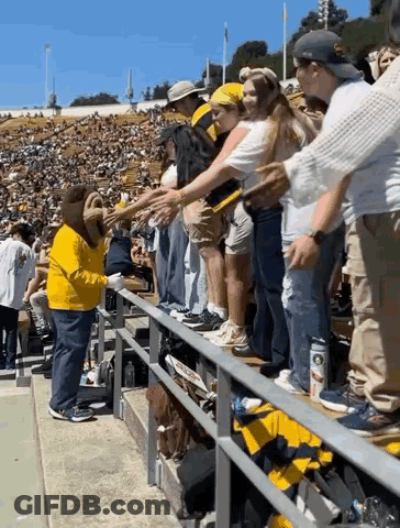 Man In Yellow Shirt Shaking Hands With Woman In Crowd GIF