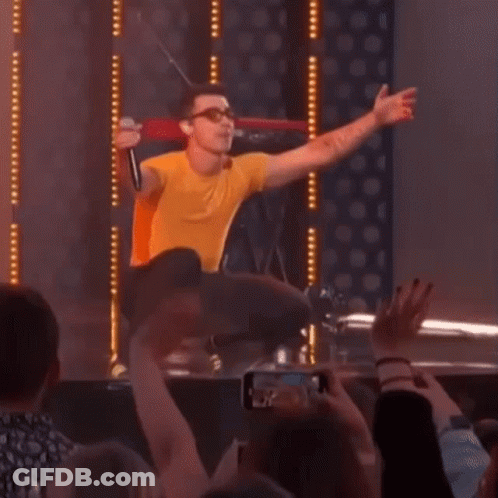 Man In Yellow Shirt Singing Into Microphone GIF