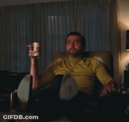Man In Yellow Shirt Sitting Holding Mug Pointing GIF