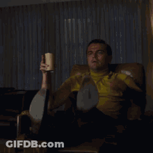 Man In Yellow Shirt Sitting In Chair Holding Cup GIF