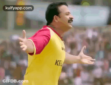 Man In Yellow Shirt Standing Before Crowd With Hands Outstretched GIF
