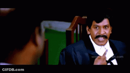 Man In Yellow Shirt Standing Before Suited Men GIF