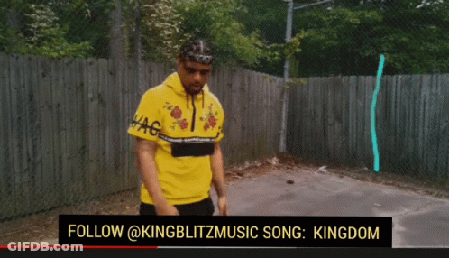 Man In Yellow Shirt Standing In Front Of Fence GIF