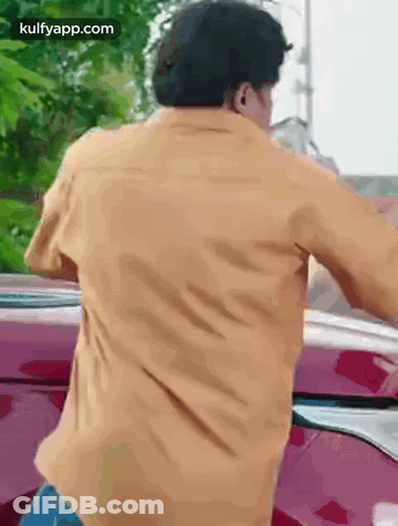 Man In Yellow Shirt Standing In Front Of Red Car GIF