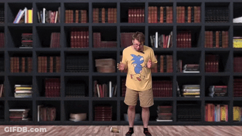 Man In Yellow Shirt With Blue Sonic In Front Of Bookshelf GIF