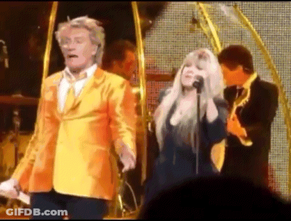Man In Yellow Suit Next To Woman Singing GIF
