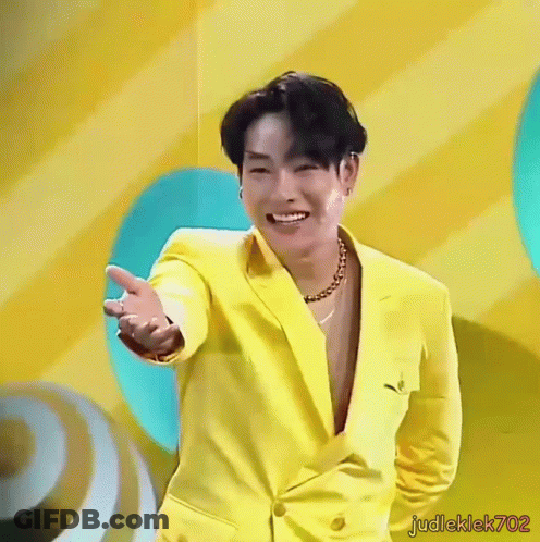 Man In Yellow Suit Smiling And Holding Out Hand GIF