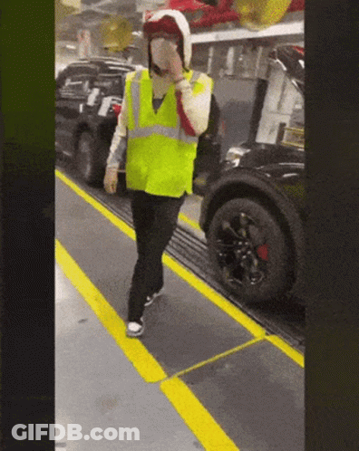 Man In Yellow Vest And Helmet On Conveyor Belt With Car GIF