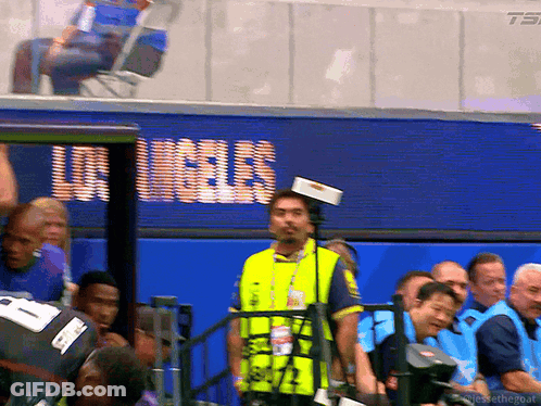 Man In Yellow Vest In Front Of Los Angeles Screen GIF