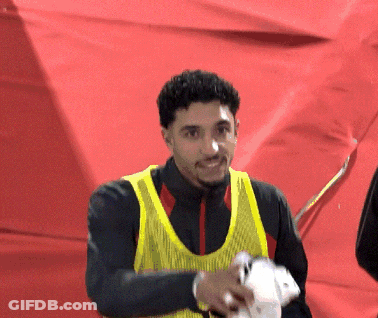 Man In Yellow Vest In Front Of Red Wall GIF