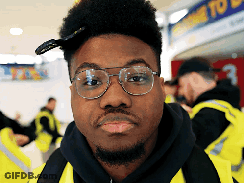 Man In Yellow Vest Looking At Camera GIF