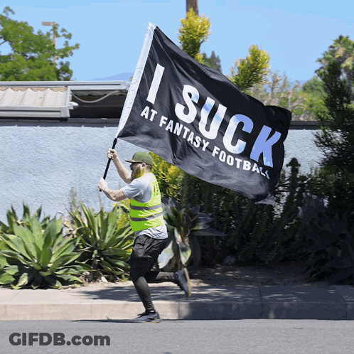 Man In Yellow Vest Running With I Suck At Fantasy Football Flag GIF