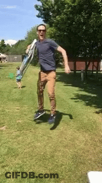 Man Jumping Holding Ladder In Park GIF