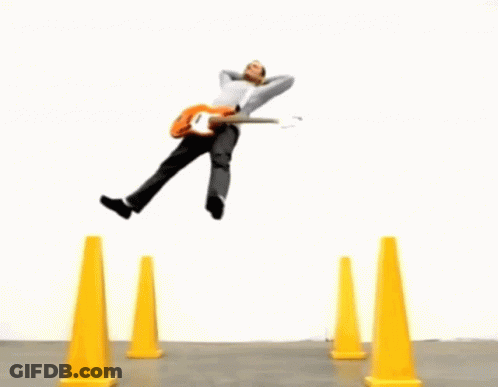 Man Jumping Over Yellow Cones Holding Pumpkin GIF