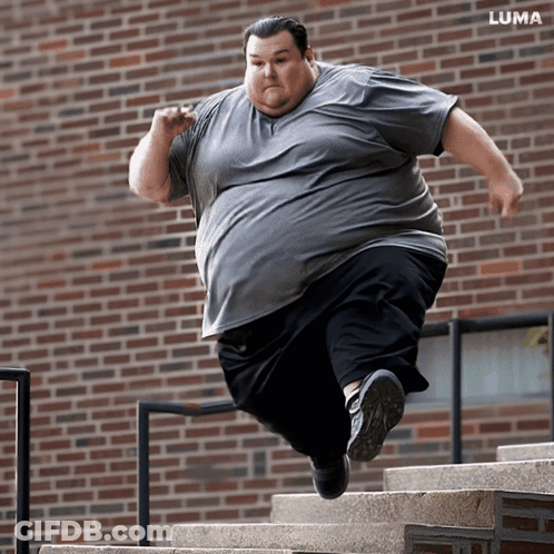 Man Jumping Up Stairs In Front Of Brick Building GIF