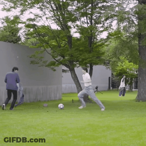 Man Kicking Soccer Ball While Another Watches GIF