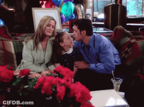 Man Kisses Little Girl On Cheek On Couch With Flowers GIF