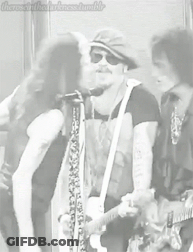 Man Kissing Another Man On Cheek Playing Guitar GIF