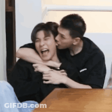 Man Kissing Another Man On Neck At Table GIF