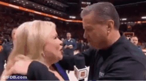 Man Kissing Woman On Cheek In Basketball Stadium GIF
