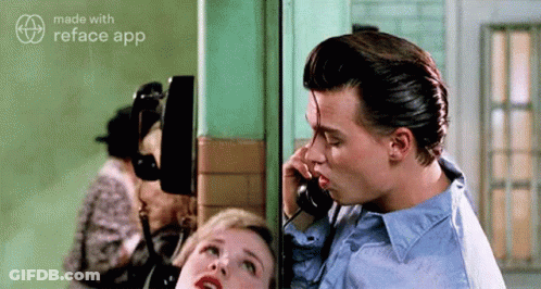 Man Kissing Woman On Cheek While Talking On Telephone GIF