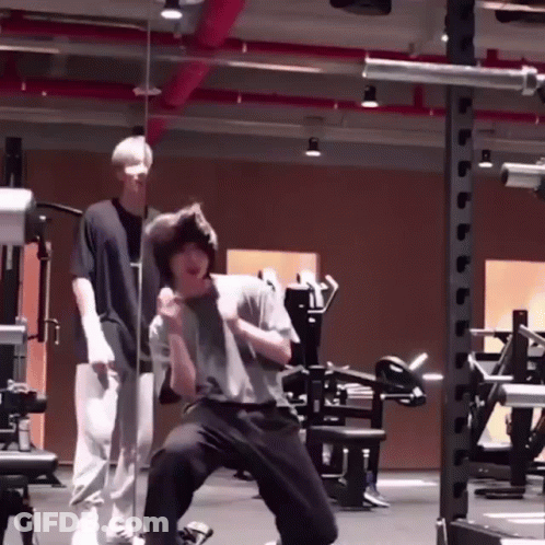 Man Kneeling In Gym With Another Man Standing Behind GIF
