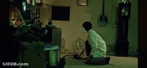 Man Kneeling In Room With Clock And Guitar GIF