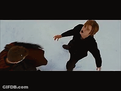 Man Kneeling In Snow While Another Rides Snowboard GIF