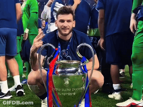 Man Kneeling Next To Champions League Trophy GIF