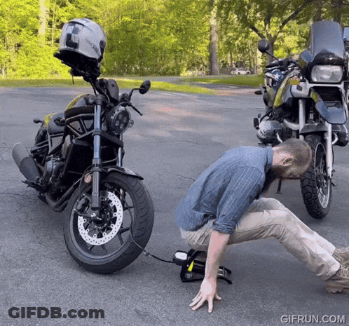 Man Kneeling Next To Motorcycle With Helmet GIF