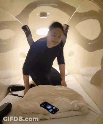 Man Kneeling On Bed With Cell Phone GIF