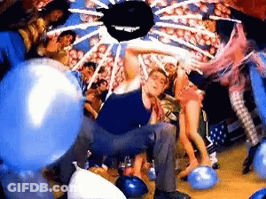Man Kneeling On Bowling Alley Surrounded By Balloons GIF