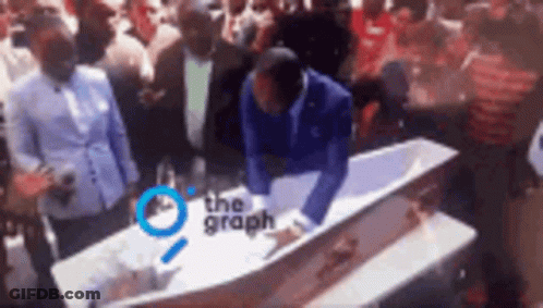 Man Kneeling Over Coffin With Crowd Surrounding GIF