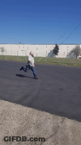 Man Kneeling While Another Man Rides Scooter GIF