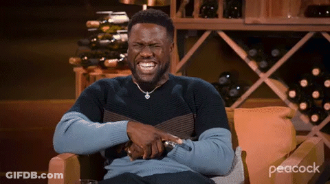 Man Laughing In Chair In Front Of Wine Shelf GIF