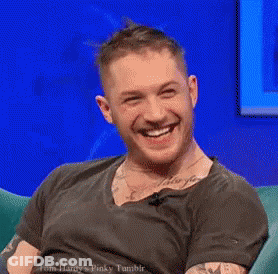 Man Laughing Sitting In Chair In Front Of Blue Wall GIF