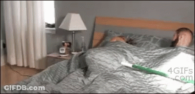 Man Laying In Bed With Lamp And Clock GIF