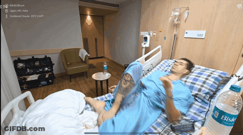 Man Laying In Hospital Bed With Bottle Of Bisk Water GIF