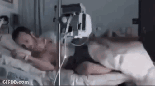 Man Laying In Hospital Bed With IV In Mouth GIF