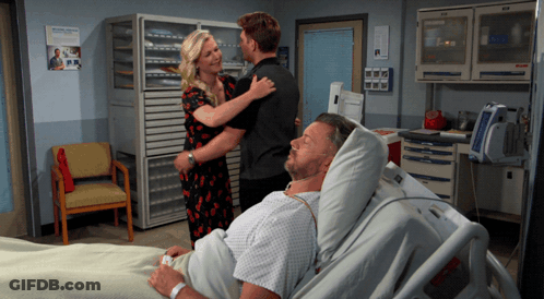 Man Laying In Hospital Bed With Woman And Man Standing Around GIF