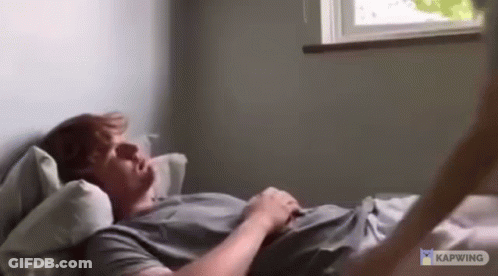 Man Laying On Bed Arms Outstretched By Window GIF