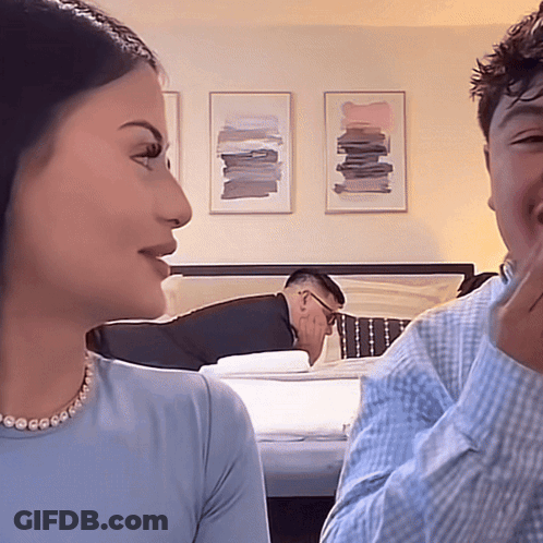 Man Laying On Bed Behind Woman GIF