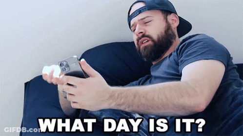 Man Laying On Bed Looking At Phone Saying What Day Is It GIF