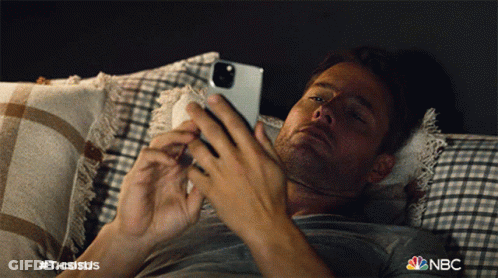 Man Laying On Bed Looking At Phone With NBC Logo GIF