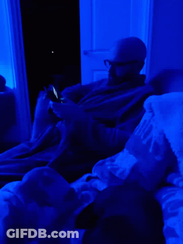 Man Laying On Bed With Blue Light And Mickey Blanket GIF