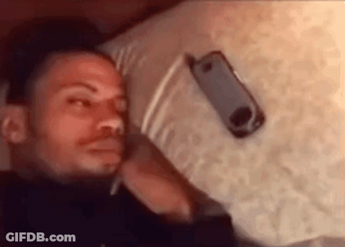 Man Laying On Bed With Cell Phone On Head GIF