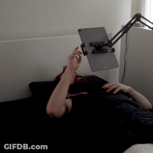 Man Laying On Bed With Tablet Holder On Head GIF
