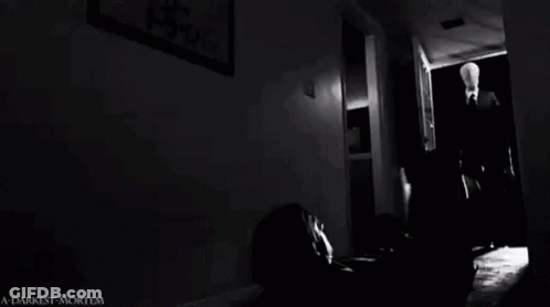 Man Laying On Floor In Dark Room With Slender Man GIF