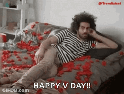 Man Laying On Rose Petal Bed Saying Happy V Day GIF