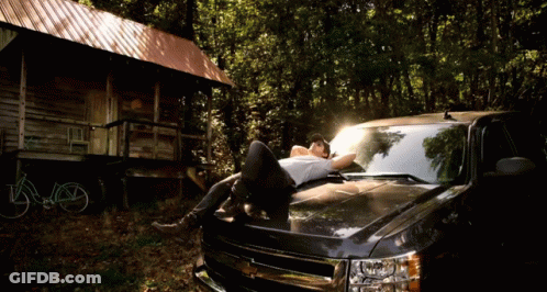 Man Laying On Truck Hood In Woods GIF